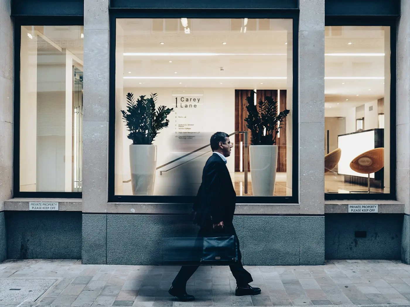 A man in a dark suit walking past a storefront