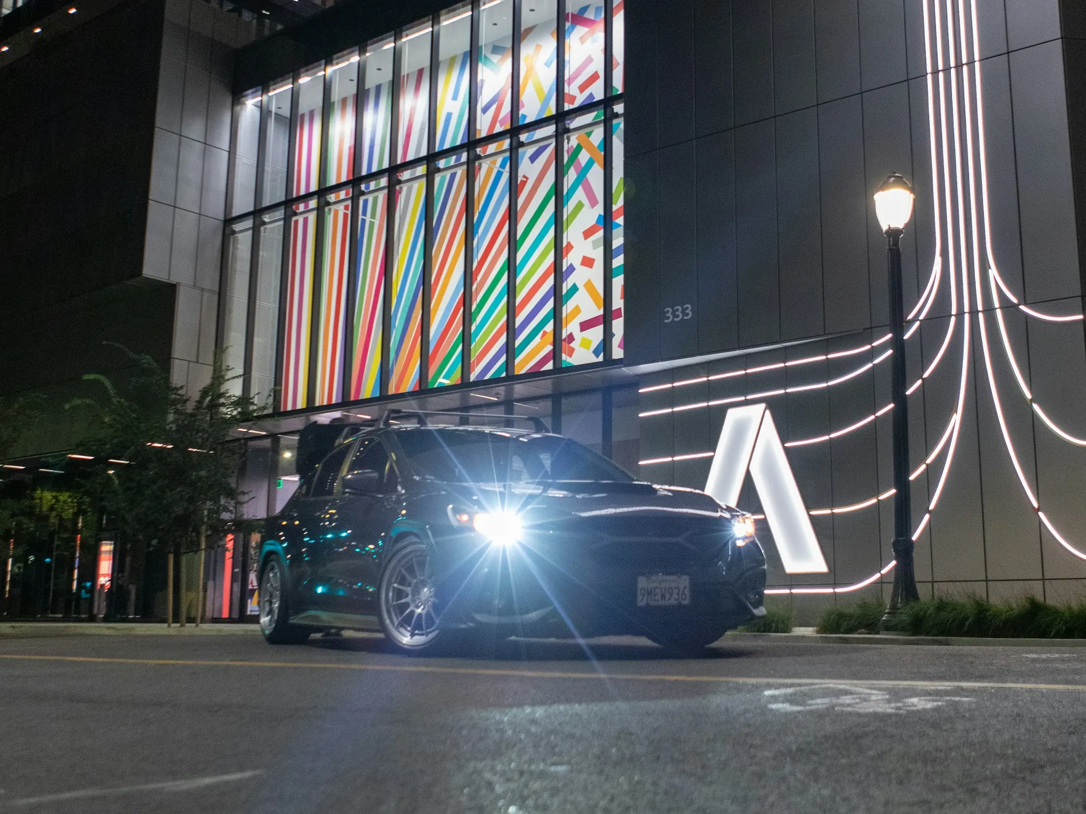 A dark SUV waiting outside a modern building at night