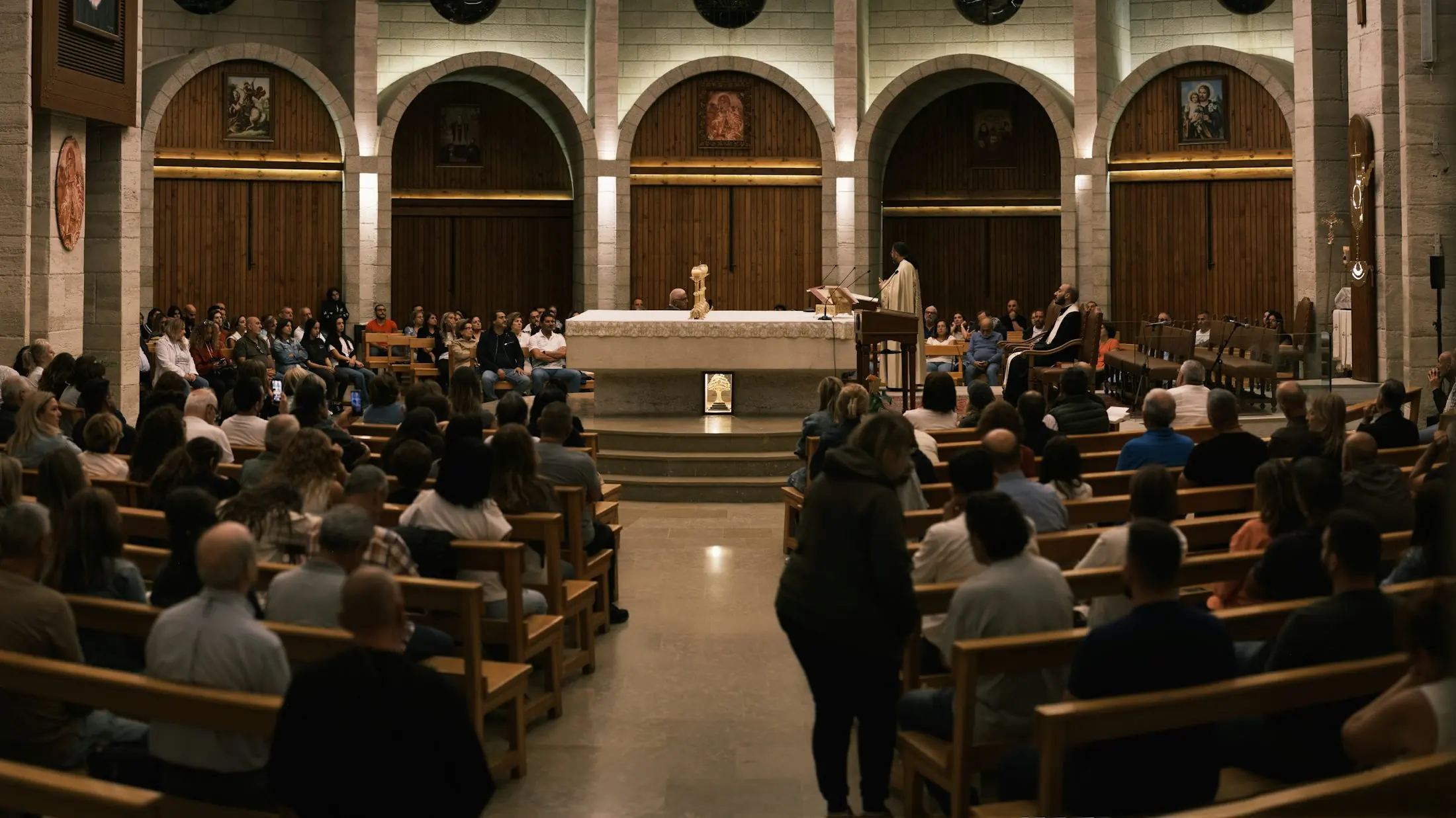 A congregation gathered for a service in a church with arched windows